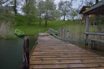 A pier in the lake near the house in countryside.