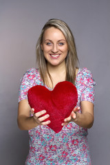 attractive smiling woman holding a red heart