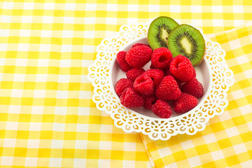 Fresh Red Raspberries on a white artistic plate / Red Fresh Raspberries on a white artistic plate with cookies, rosemary, chocolate and cream in the background.