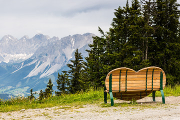 Obraz premium heart-shaped bench on pasture with mountain view