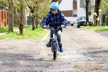 The boy on the bike riding on the puddles
