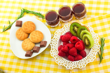 Fresh Red Raspberries on a white artistic plate / Red Fresh Raspberries on a white artistic plate with cookies, rosemary, chocolate and cream in the background.
