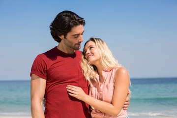 Couple with arm around standing on shore at beach