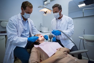 Naklejka na ściany i meble Dentists examining a female patient with tools