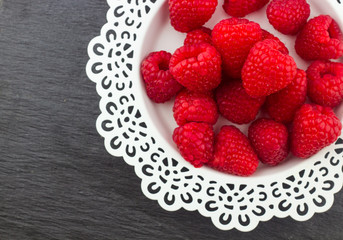 Fresh Red Raspberries on a white artistic plate / Red Fresh Raspberries on a white artistic plate with cookies, rosemary, chocolate and cream in the background.