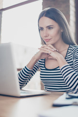 Vertical close up portrait of concentrated minded businesswoman with crossed hands  under her chin working with computer