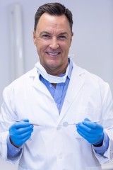 Fototapeta premium Portrait of smiling dentist holding dental tools