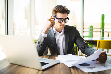 Business man working at office with laptop and documents on his desk. Analyze plans, papers, hands keyboard.