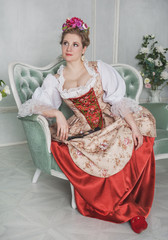 Beautiful woman in old-fashioned medieval dress on the sofa