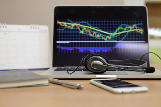 close up on headset call center desk with stock market screen laptop:currency exchange callcenter workstation:business and  technology concept