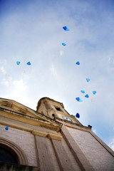 Fototapeta na wymiar palloncini blu volano nel cielo di fronte al campanile di una chiesa