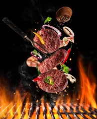 Foto auf Acrylglas Fleish Flying raw milled beef meat with ingredients above grill fire