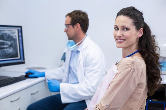 Female patient smiling while dentist working