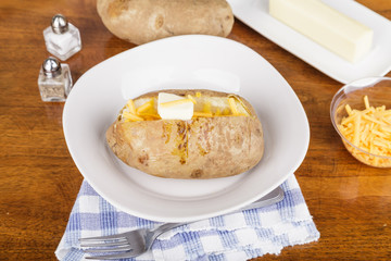Baked Potato on White Plate with Cheese and Butter