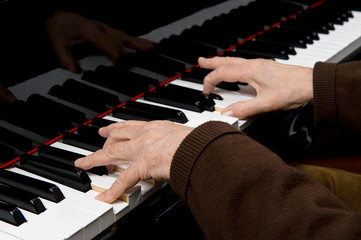 Senior male adult playing a baby grand piano