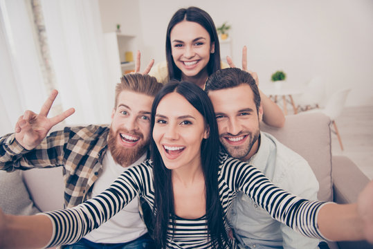 Say Cheese! Close up of an excited friend`s selfie, taken at home. Young people enjoy their company, smiling and showing two fingers sign