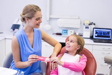 Mother giving tooth brush to daughter at dental clinic
