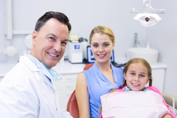 Portrait of dentist with young patient and his mother