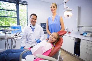 Portrait of dentist with young patient and his mother