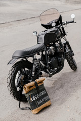 Fototapeta na wymiar Leather backpack near the motorcycle. Half black motorcycle in the garage. Motorcycle kaferacers.