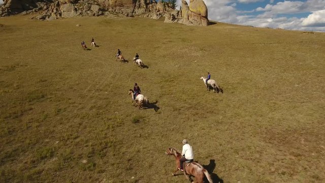 Park Terelj rocks and steppe near Ulaanbaatar Mongolia. Summer autumn sunny blue sky clouds. Beautiful Mongolian nature. Aerial drone helicopter flight follow nomads horseman riders