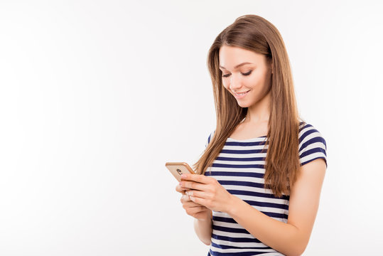 Pretty young woman in striped t-shirt isolated on white background holding a smartphone and sending sms