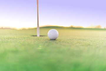 Golf ball close to hole on green, close up super wide angle.  Lots of opportunity for copy text.