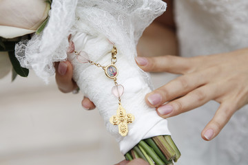 rosario con croce d'oro intorno a mazzo di fiori con mano che lo tiene