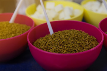 Soluble coffee in a pink plate and sugar refined in a yellow plate