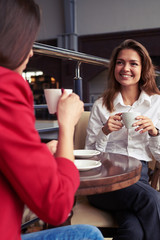 Two marvelous female drinking coffee and enjoying conversation