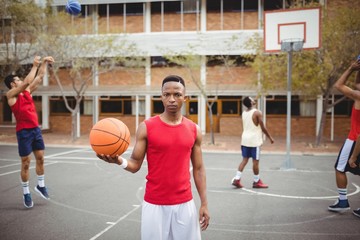 Fototapeta premium Male basketball player holding basketball in basketball court