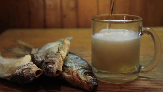 Beer and dried fish on a wooden table.