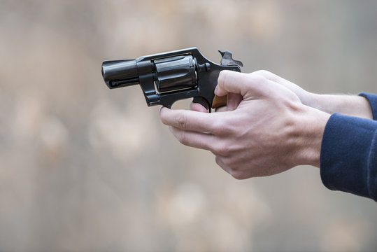 Young man holding and aiming a 38 special pistol with a shallow depth of field