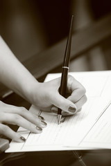 foto b/n di una mano che firma con una penna un  documento