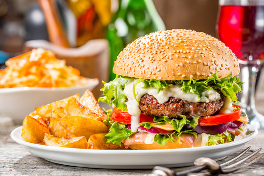 An american burger with fried potatoes on the white plate.