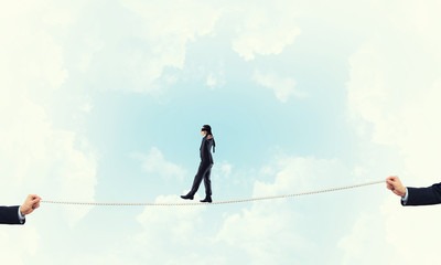 Business concept of risk support and assistance with man balancing on rope