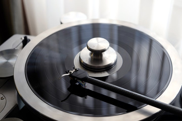 Tonearm of vintage turntable with LP record close up view