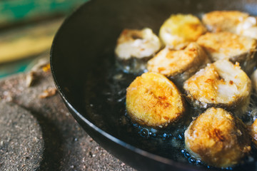 Frying hake fish slices in pan outdoors on picnic