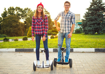 Young couple riding hoverboard - electrical scooter, personal eco transport, gyro scooter, smart balance wheel