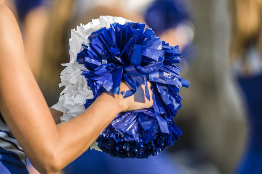 Cheerleader holding pom poms with a shallow depth of field
