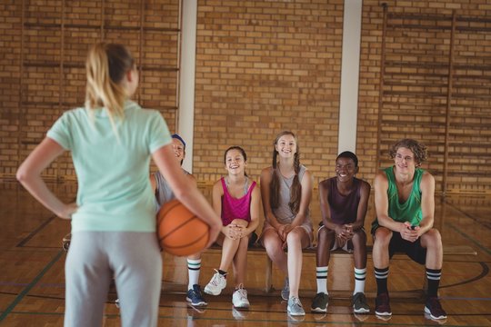 Female coach standing with basketball in basketball court