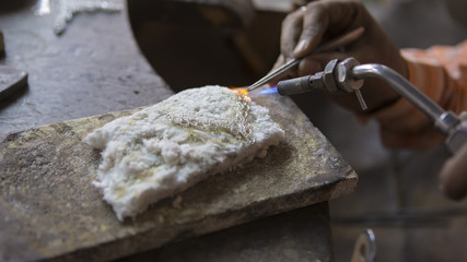 Indian Jeweler making an Oriental Jewelry in workshop. Handmade traditional jewel Manufacturing in...