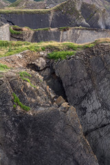 Rocky coast in Hartland Quay. Plasts are similar to plates. In the distance one can see a small figure of a climber.  An interesting natural background. Devon. England