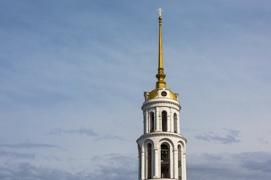 White stone bell tower with a Golden spire.