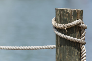 Wooden pier post and rope tied to it with a shallow depth of field - Powered by Adobe