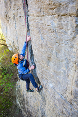 Kid rock climber climbs the cliff.