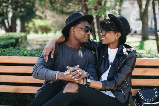 A beautiful and stylish young african couple in sunglasses and hats embracing on a outdoor of summer.