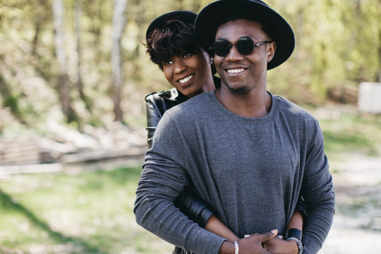 A beautiful and stylish young african couple in sunglasses and hats embracing on a outdoor of summer.