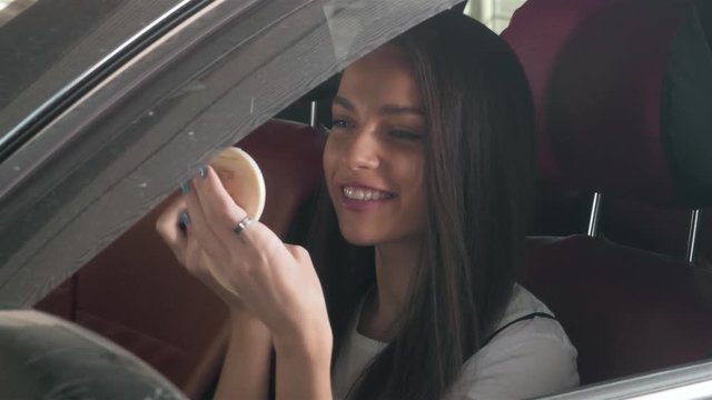 beautiful woman doing makeup in the business class car with red chairs