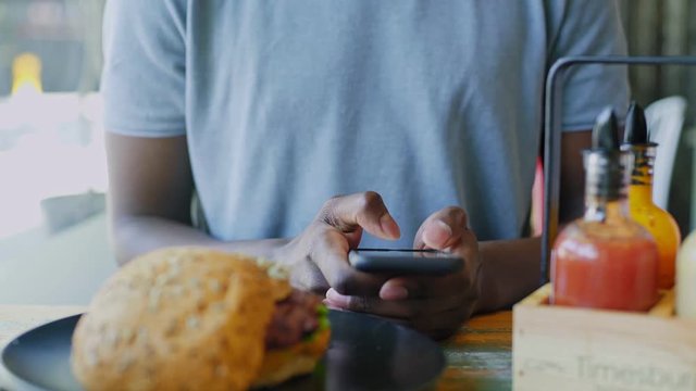 Static shot close focus of unrecognizable friend on the dinner who does not pay attention to his friends and uses his smartphone to text and chat, being antisocial and unfriendly